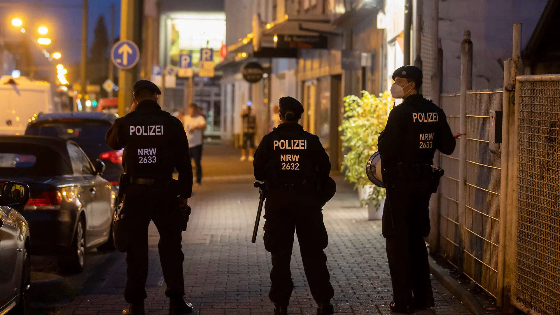 16.08.2020, Nordrhein-Westfalen, Duisburg: Drei Polizeikräfte stehen während einer Razzia an der Weseler Straße. Die nordrhein-westfälische Polizei und mehrere Behörden sind am Samstagabend in acht Städten gegen Clankriminalität vorgegangen. In Essen wurden Wettbüros und Spielautomaten-Geschäfte unter die Lupe genommen. Auch Kulturvereine und Teestuben wurden durchsucht. Foto: Christoph Reichwein (crei)/dpa +++ dpa-Bildfunk +++
