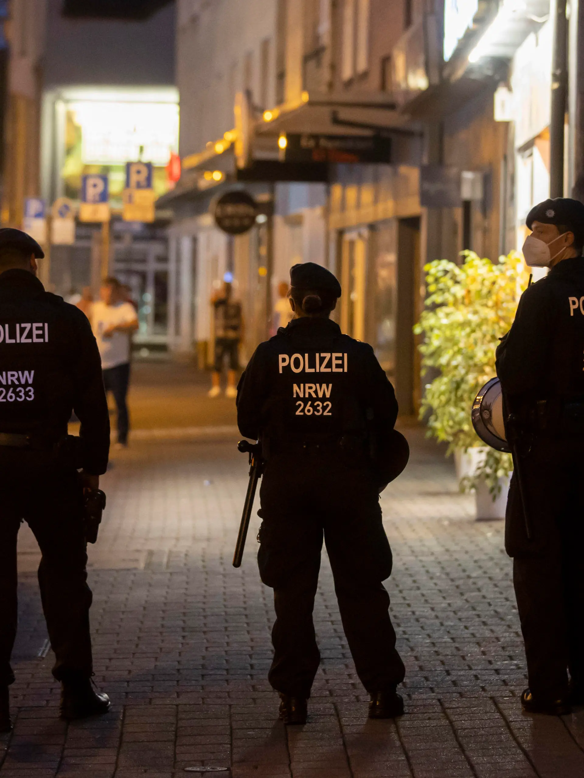 16.08.2020, Nordrhein-Westfalen, Duisburg: Drei Polizeikräfte stehen während einer Razzia an der Weseler Straße. Die nordrhein-westfälische Polizei und mehrere Behörden sind am Samstagabend in acht Städten gegen Clankriminalität vorgegangen. In Essen wurden Wettbüros und Spielautomaten-Geschäfte unter die Lupe genommen. Auch Kulturvereine und Teestuben wurden durchsucht. Foto: Christoph Reichwein (crei)/dpa +++ dpa-Bildfunk +++