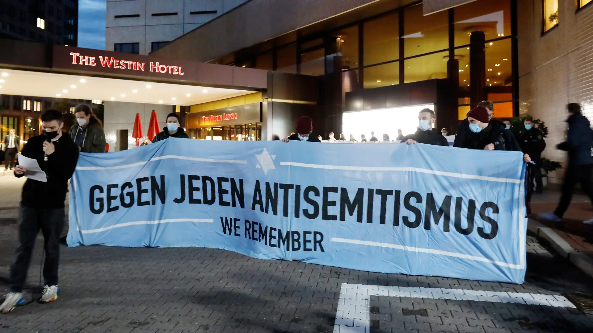 05.10.2021, Sachsen, Leipzig: Teilnehmer einer Demonstration des Bündnis "Leipzig nimmt Platz" stehen vor dem «Westin Hotel» Leipzig. Nach Antisemitismus-Vorwürfen haben sich am Abend Hunderte Menschen vor dem «Westin Hotel» Leipzig versammelt, um Solidarität mit dem Musiker Gil Ofarim und Jüdinnen und Juden in Deutschland zu zeigen. Ofarim war am Montag nach eigenen Angaben Opfer eines antisemitischen Vorfalls in dem Leipziger Hotel geworden. Ein Mitarbeiter des «Westin Leipzig» habe ihn am Empfang aufgefordert, seinen Davidstern einzupacken. Dann dürfe er einchecken. Foto: Dirk Knofe/dpa +++ dpa-Bildfunk +++