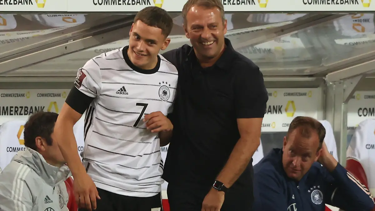 STUTTGART, GERMANY - SEPTEMBER 05: Hans-Dieter Flick, head coach of Germany jokes with his player Florian Wirtz prior to his substitution during the 2022 FIFA World Cup Qualifier match between Germany and Armenia at Mercedes-Benz Arena on September 05, 2021 in Stuttgart, Germany. (Photo by Alexander Hassenstein/Getty Images)