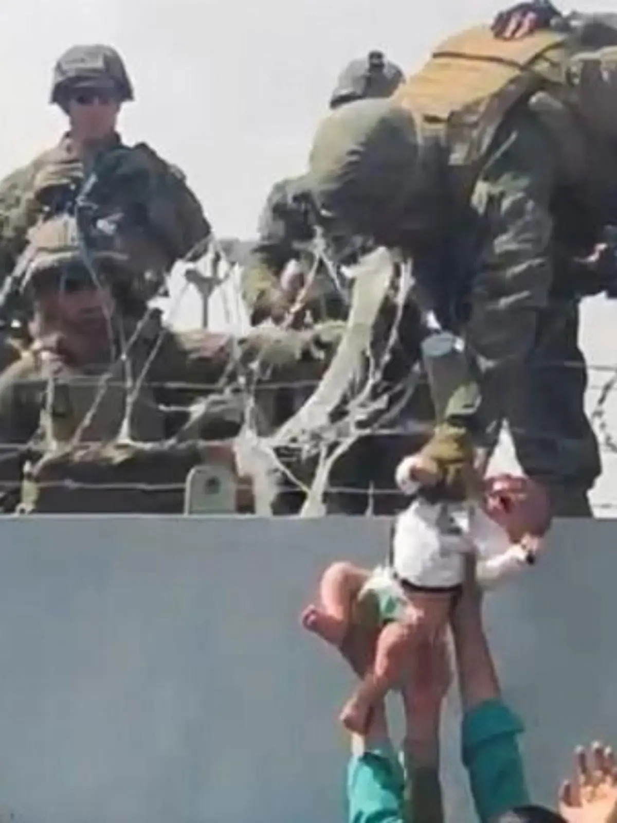 FILE PHOTO: A baby is handed over to the American army over the perimeter wall of the airport for it to be evacuated, in Kabul, Afghanistan, August 19, 2021. OMAR HAIDARI/via REUTERS/File Photo