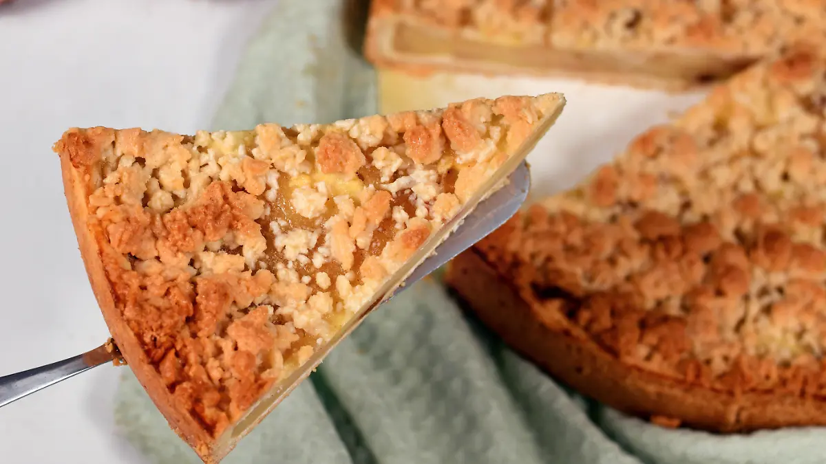 Slice of traditional European apple pie with topping crumbles called 'Streusel' on cake server