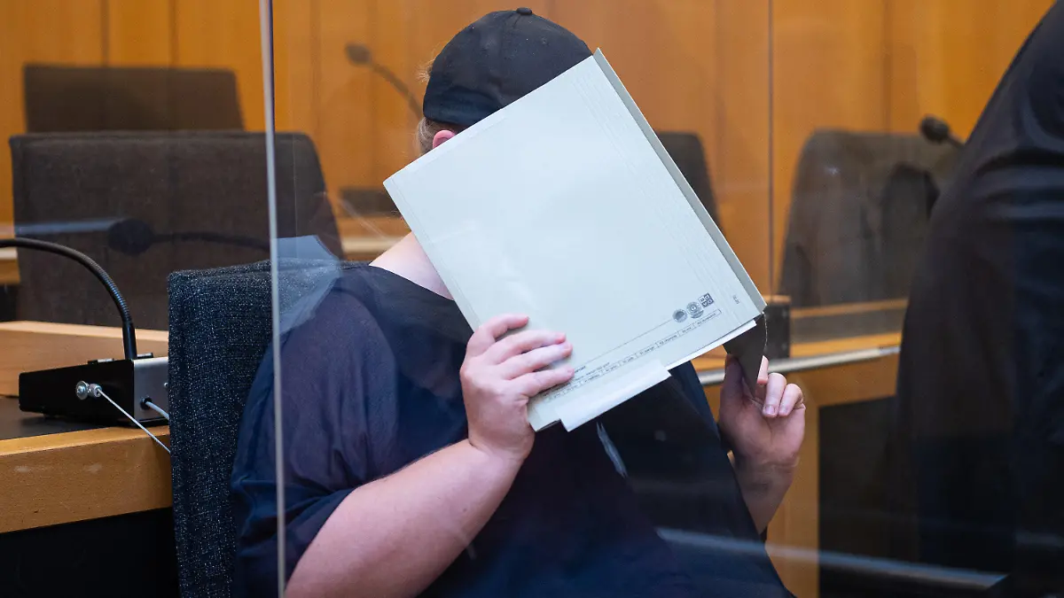 ARCHIV - 05.08.2021, Nordrhein-Westfalen, Münster: Zu Beginn des Prozesses im Missbrauchskomplex Münster sitzt die Mutter eines Opfers im Landgericht Münster und verdeckt ihr Gesicht mit einer Mappe. Die Anklage wirft der 31-Jährigen vor, den schweren sexuellen Missbrauch ihres heute elfjährigen Sohnes durch ihren Lebensgefährten nicht verhindert zu haben, obwohl sie davon wusste. Der IT-Techniker wurde im Hauptprozess zu 14 Jahren Haft und anschließender Sicherungsverwahrung verurteilt. (zu dpa: (Landgericht spricht Urteil gegen Mutter im Missbrauchskomplex Münster») Foto: Guido Kirchner/dpa +++ dpa-Bildfunk +++