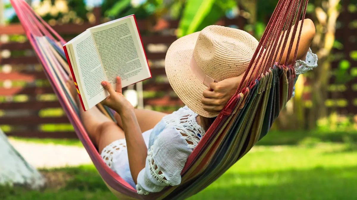 Woman reading book in hammock in tropical garden