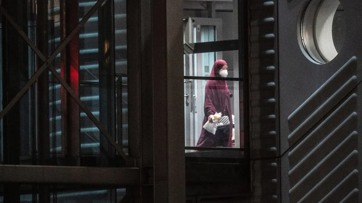 07.10.2021, Hessen, Frankfurt/Main: Eine verschleierte Frau mit einer Maske betritt aus der Gangway einer Chartermaschine heraus einen abgeschirmten Bereich der Bundespolizei am Flughafen Frankfurt. In einer zunächst geheim gehaltenen Aktion hatte die Bundesregierung in Zusammenarbeit mit der US-Armee insgesamt acht deutsche Anhängerinnen der Terrormiliz ·Islamischer Staat· (IS) mit ihren 23 Kindern im Rahmen einer humanitären Aktion aus einem Gefangenenlager in Syrien geholt. Mit einer Chartermaschine wurden die Frauen über Kuwait nach Deutschland gebracht, wo fast alle sofort in Haft genommen wurden. Foto: Boris Roessler/dpa +++ dpa-Bildfunk +++