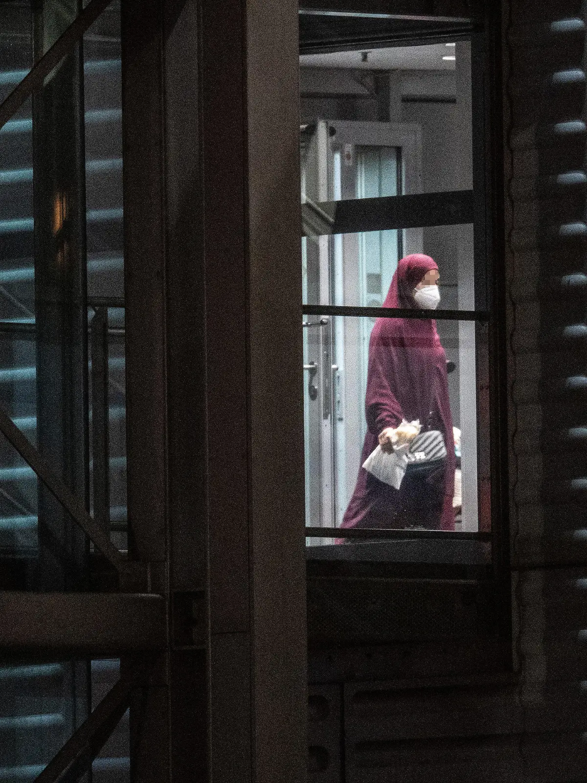 07.10.2021, Hessen, Frankfurt/Main: Eine verschleierte Frau mit einer Maske betritt aus der Gangway einer Chartermaschine heraus einen abgeschirmten Bereich der Bundespolizei am Flughafen Frankfurt. In einer zunächst geheim gehaltenen Aktion hatte die Bundesregierung in Zusammenarbeit mit der US-Armee insgesamt acht deutsche Anhängerinnen der Terrormiliz ·Islamischer Staat· (IS) mit ihren 23 Kindern im Rahmen einer humanitären Aktion aus einem Gefangenenlager in Syrien geholt. Mit einer Chartermaschine wurden die Frauen über Kuwait nach Deutschland gebracht, wo fast alle sofort in Haft genommen wurden. Foto: Boris Roessler/dpa +++ dpa-Bildfunk +++