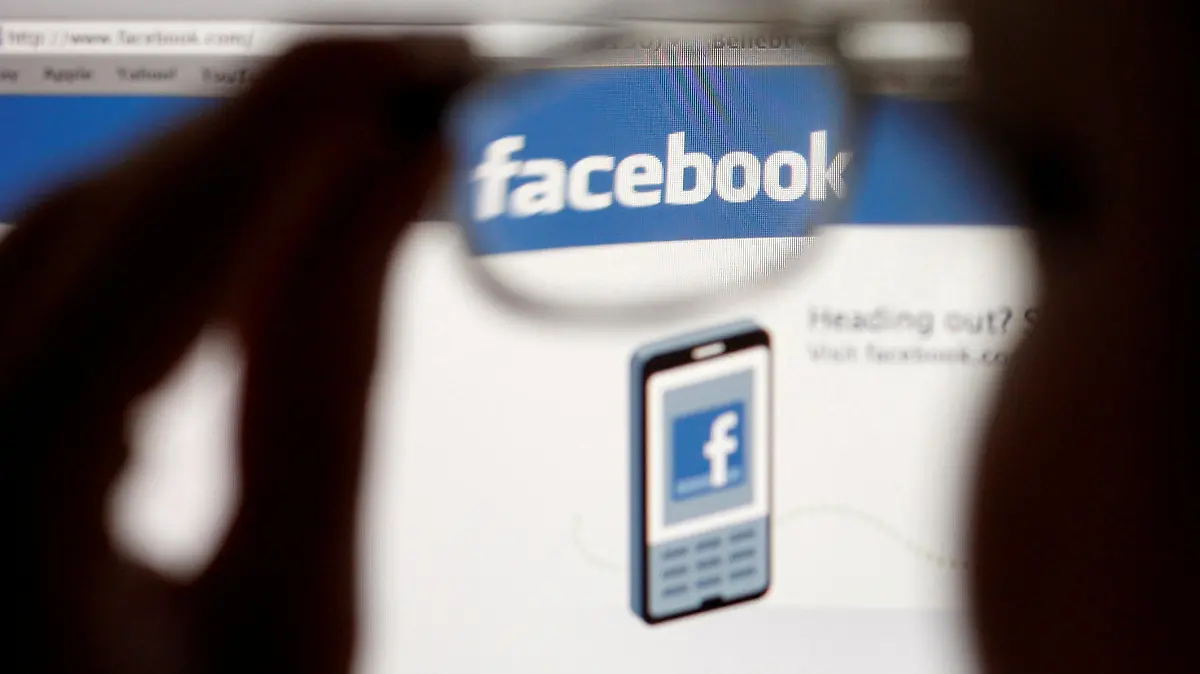 FILE PHOTO: In this photo illustration, a Facebook logo on a computer screen is seen through glasses held by a woman in Bern May 19, 2012. Picture taken May 19, 2012. REUTERS/Thomas Hodel/File Photo