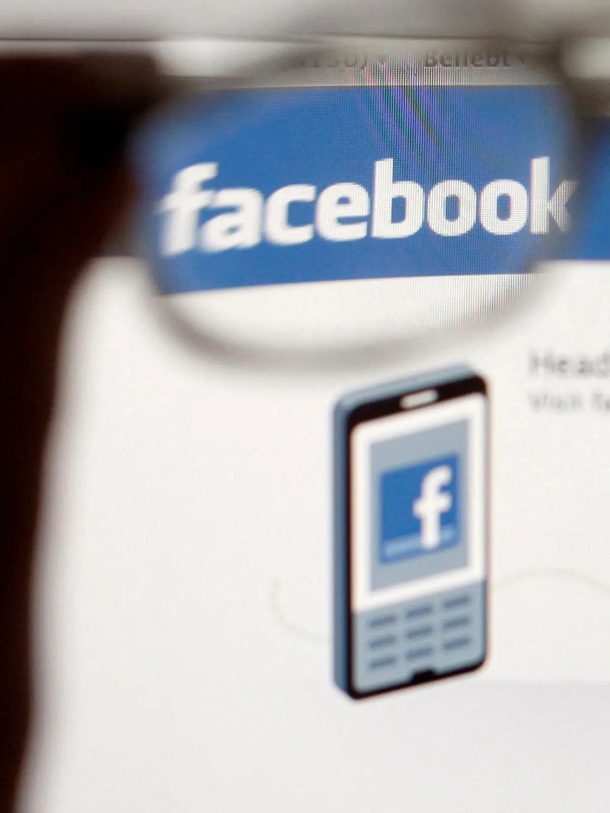 FILE PHOTO: In this photo illustration, a Facebook logo on a computer screen is seen through glasses held by a woman in Bern May 19, 2012. Picture taken May 19, 2012. REUTERS/Thomas Hodel/File Photo