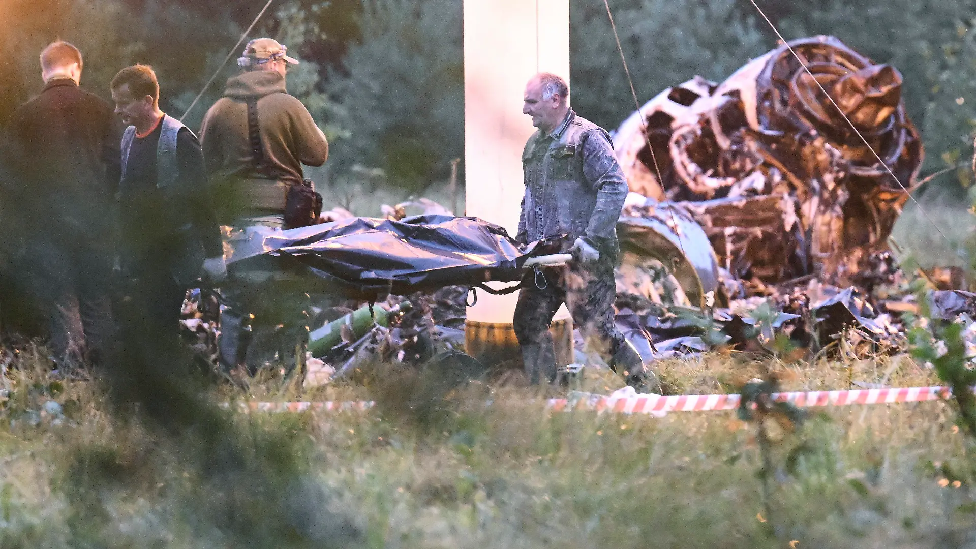 24.08.2023, Russland, Kushenkino: Menschen tragen einen Leichensack aus dem Wrack eines abgestürzten Privatjets in der Nähe des Dorfes Kuschenkino in der Region Twer. Der russische Söldnerführer Jewgeni Prigoschin ist nach Angaben seines Telegram-Kanals Grey Zone vom Mittwoch tot. Von offizieller Seite steht eine Bestätigung aus. Nach russischen Behördenangaben stand er aber auf der Passagierliste eines abgestürzten Flugzeugs. Foto: Uncredited/AP/dpa +++ dpa-Bildfunk +++