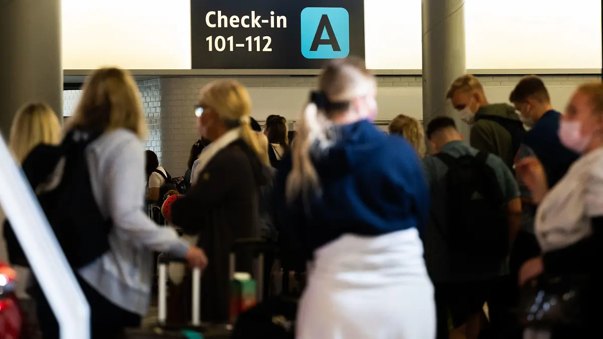 ARCHIV - 21.07.2021, Niedersachsen, Hannover: Menschen warten am Flughafen Hannover beim Check-In auf ihre Anmeldung. Derzeit brauchen Flugreisende viel Geduld. Bei den Sicherheitskontrollen am Flughafen Hannover kommt es zu langen Wartezeiten. (zu dpa: «Lange Wartezeit am Flughafen Hannover - Bundespolizei plant Taskforce») Foto: Julian Stratenschulte/dpa +++ dpa-Bildfunk +++