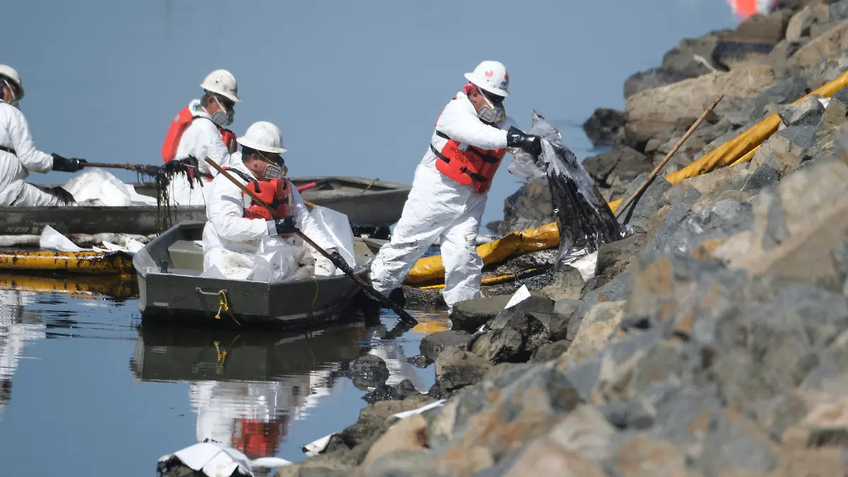 03.10.2021, USA, Huntington Beach: Reinigungskräfte laden das aufgefangene Öl in Plastiksäcke ab, um ein weiteres Eindringen des Öls in die Wetlands Talbert Marsh in Huntington Beach, Kalifornien, zu verhindern. Eine der größten Ölverschmutzungen in der jüngeren Geschichte Südkaliforniens verschmutzte beliebte Strände und tötete Wildtiere, während sich die Einsatzkräfte am Sonntag bemühten, das Öl einzudämmen, bevor es sich weiter in geschützte Feuchtgebiete ausbreiten konnte. Foto: Ringo H.W. Chiu/AP/dpa +++ dpa-Bildfunk +++