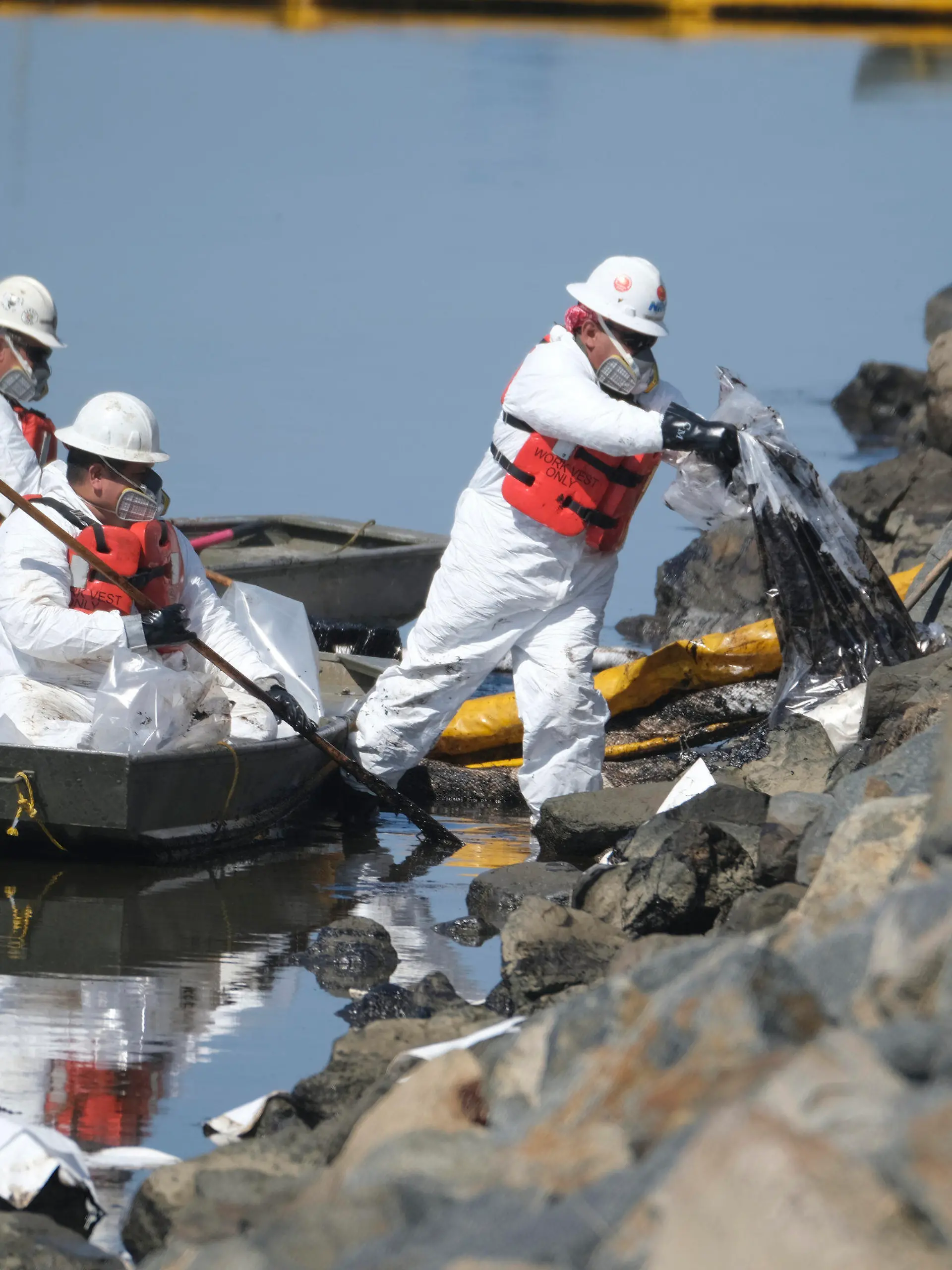 03.10.2021, USA, Huntington Beach: Reinigungskräfte laden das aufgefangene Öl in Plastiksäcke ab, um ein weiteres Eindringen des Öls in die Wetlands Talbert Marsh in Huntington Beach, Kalifornien, zu verhindern. Eine der größten Ölverschmutzungen in der jüngeren Geschichte Südkaliforniens verschmutzte beliebte Strände und tötete Wildtiere, während sich die Einsatzkräfte am Sonntag bemühten, das Öl einzudämmen, bevor es sich weiter in geschützte Feuchtgebiete ausbreiten konnte. Foto: Ringo H.W. Chiu/AP/dpa +++ dpa-Bildfunk +++