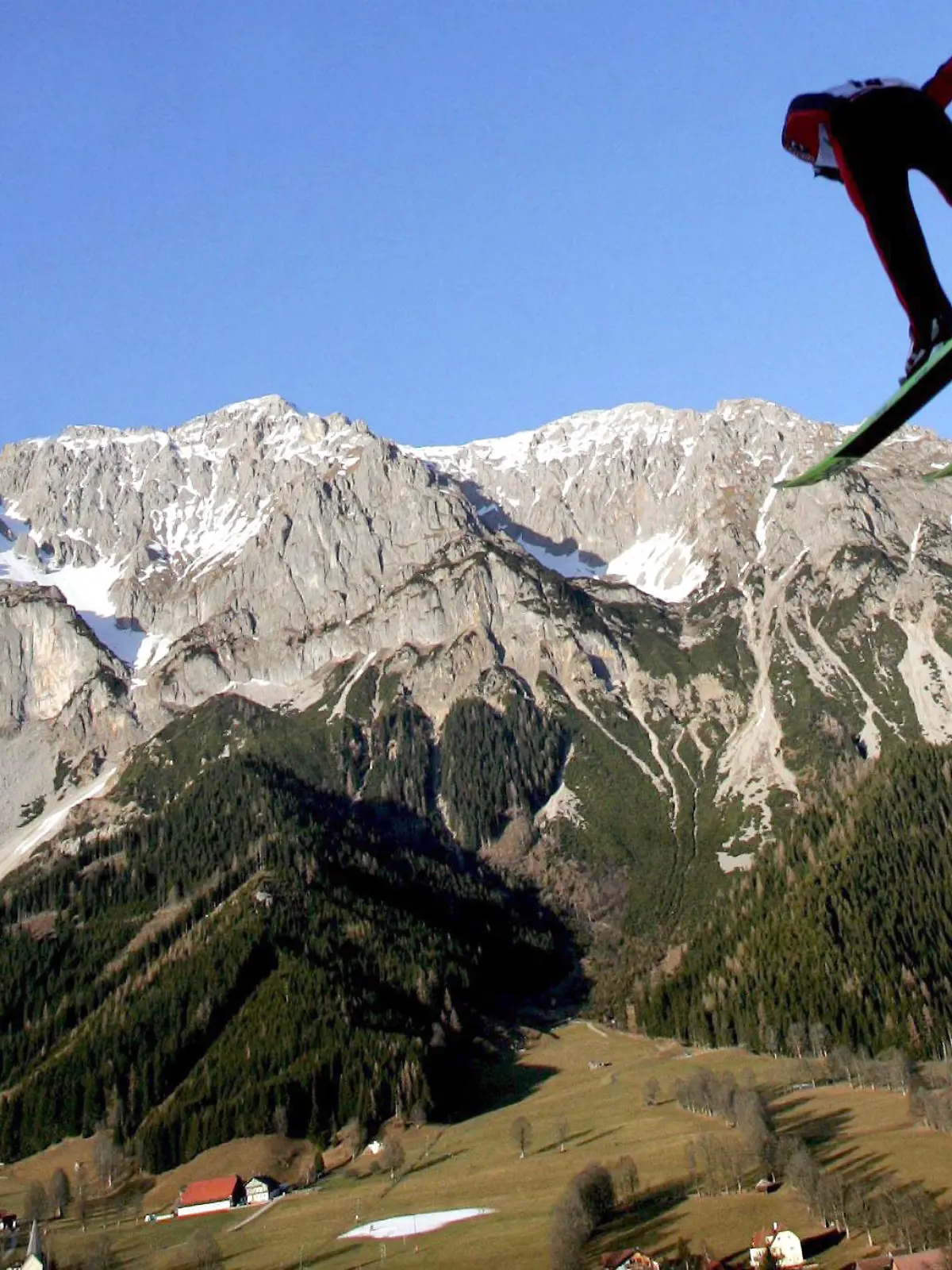 Ein Skispringer bei der Nordischen Kombination am 16.12.2006 in Ramsau (Österreich) scheint auf einen fast schneefreien Gebirgszug zuzuspringen. Der Klimawandel gefährdet nahezu alle Wintersportgebiete in Deutschland und fast drei Viertel der Skiregionen in Österreich. In den vergangenen 25 Jahren stieg die Temperatur in den Alpen laut OECD drei Mal so schnell wie im weltweiten Durchschnitt. EPA/HELMUT FOHRINGER (zu dpa-Themenpaket "Klimawandel in den Alpen" vom 15.12.2006)   +++(c) dpa - Bildfunk+++