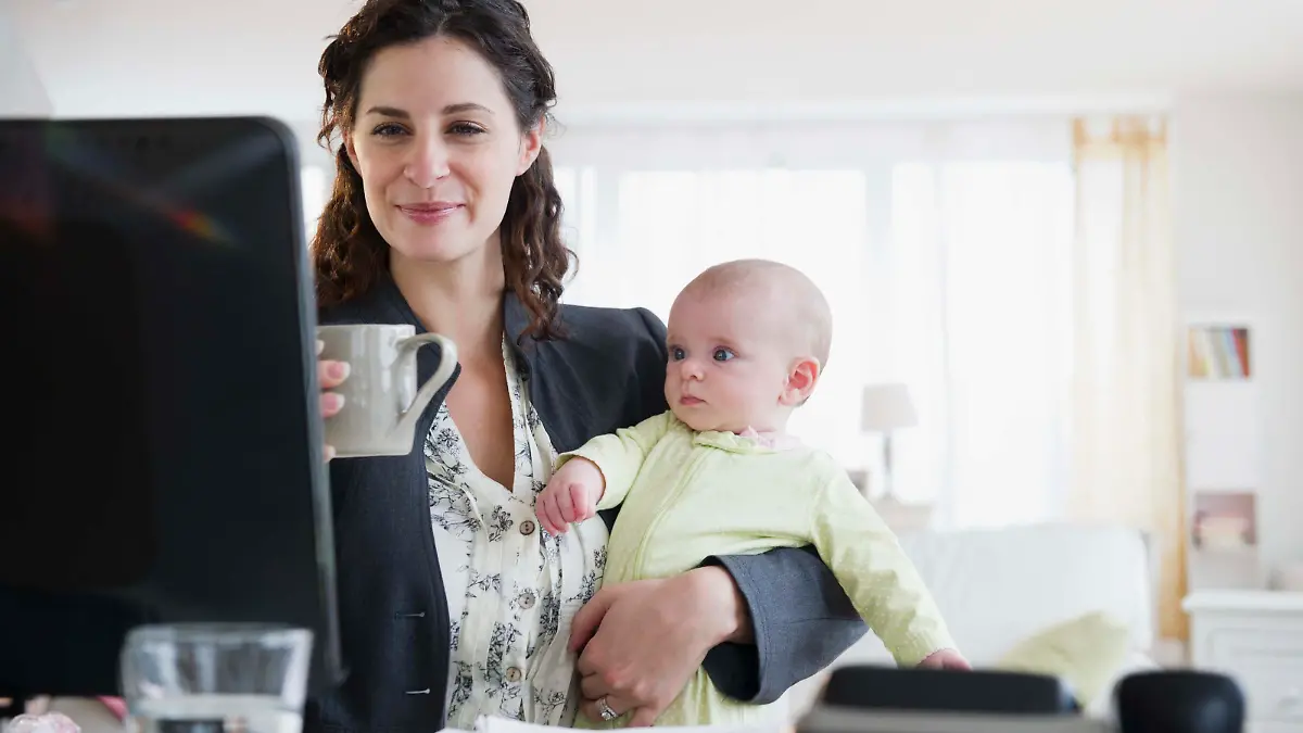 Mother with baby boy (2-5 months) working from home, Frau arbeitet am Computer und hält dabei Baby im Arm Keine Weitergabe an Drittverwerter.
