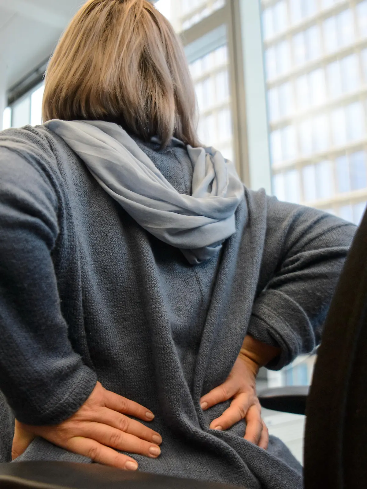 Illustration - Eine Frau fasst sich am 26.10.2018 in Berlin mit der Hand an den Ruecken (Gestellte Szene). Foto: Sina Schuldt