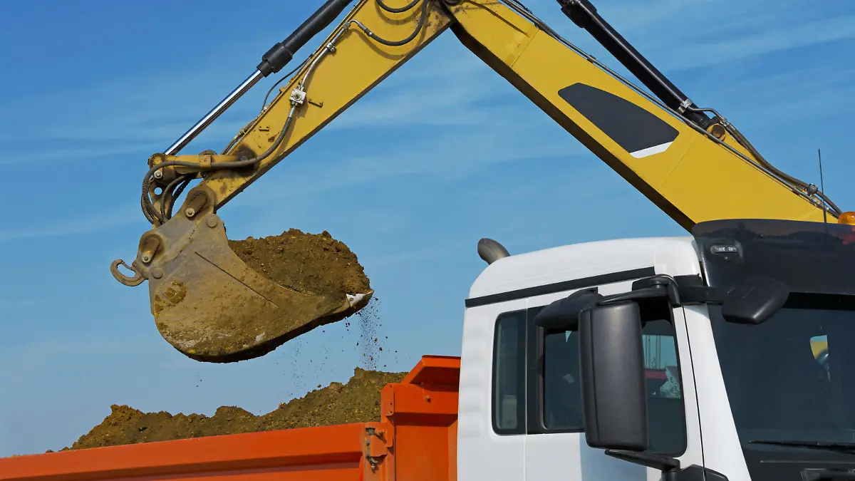 Bagger balädt LKW. Excavator loads a trucks with excavation.
