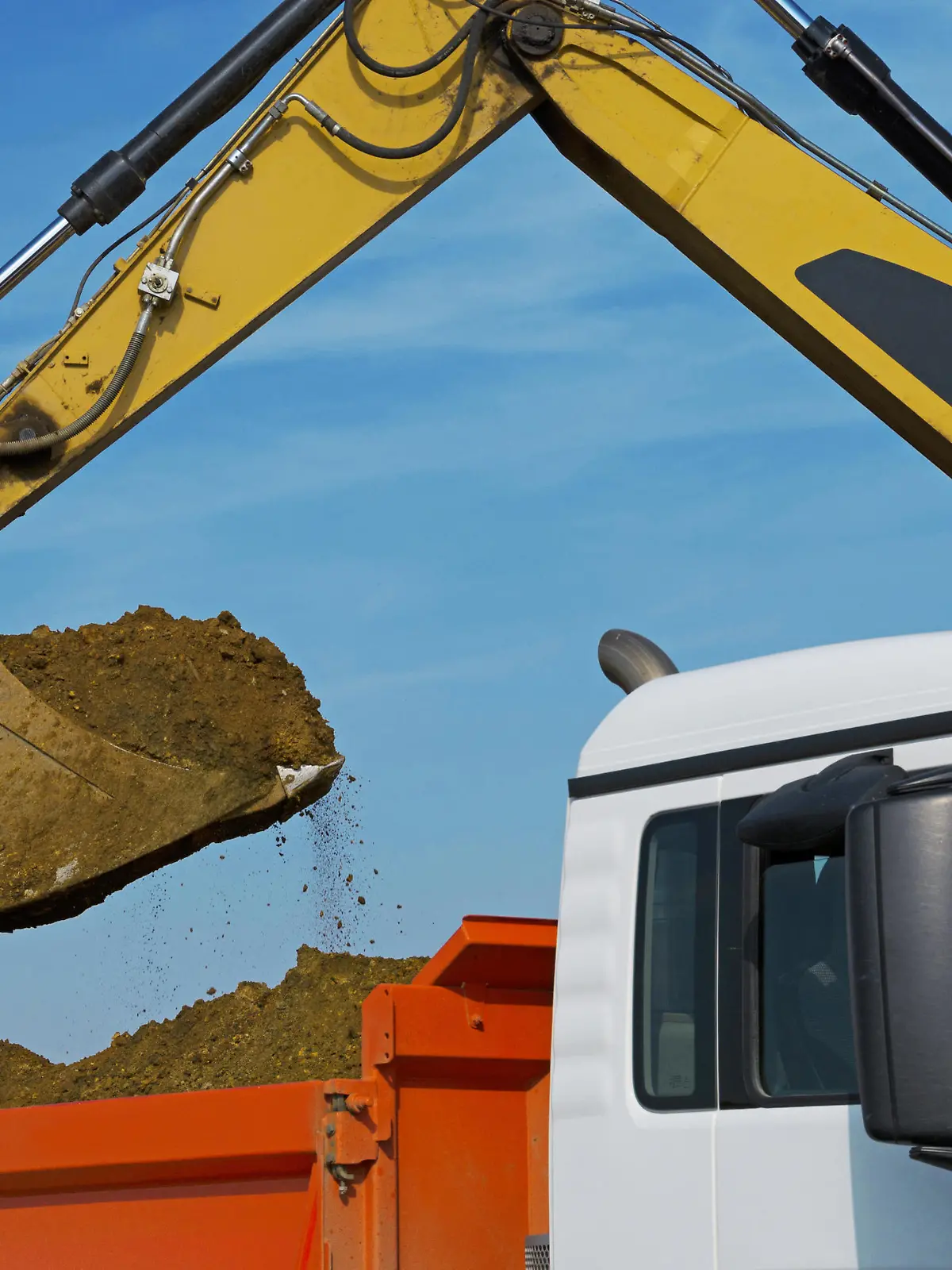 Bagger balädt LKW. Excavator loads a trucks with excavation.