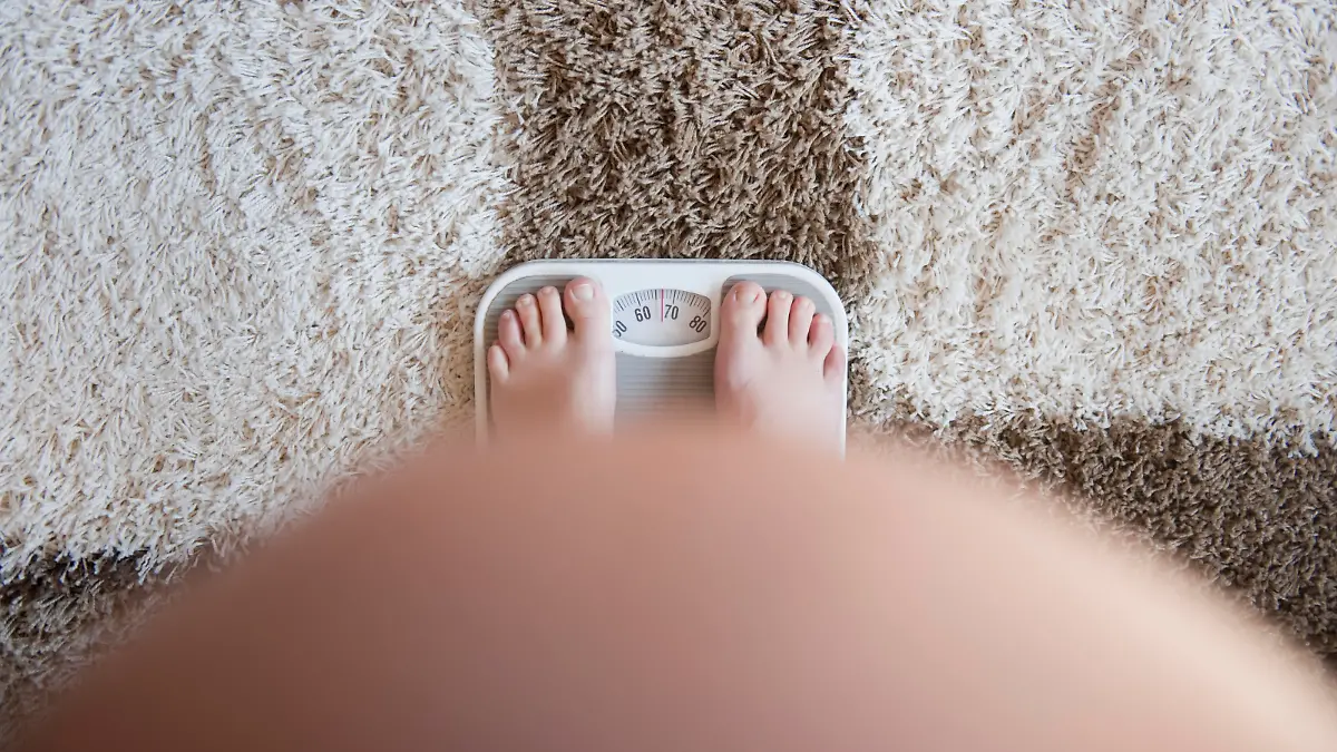 Pregnant woman weighting herself on a bathroom scale. View from above. No face. Focus on weight scale . Self portret Shallow dof