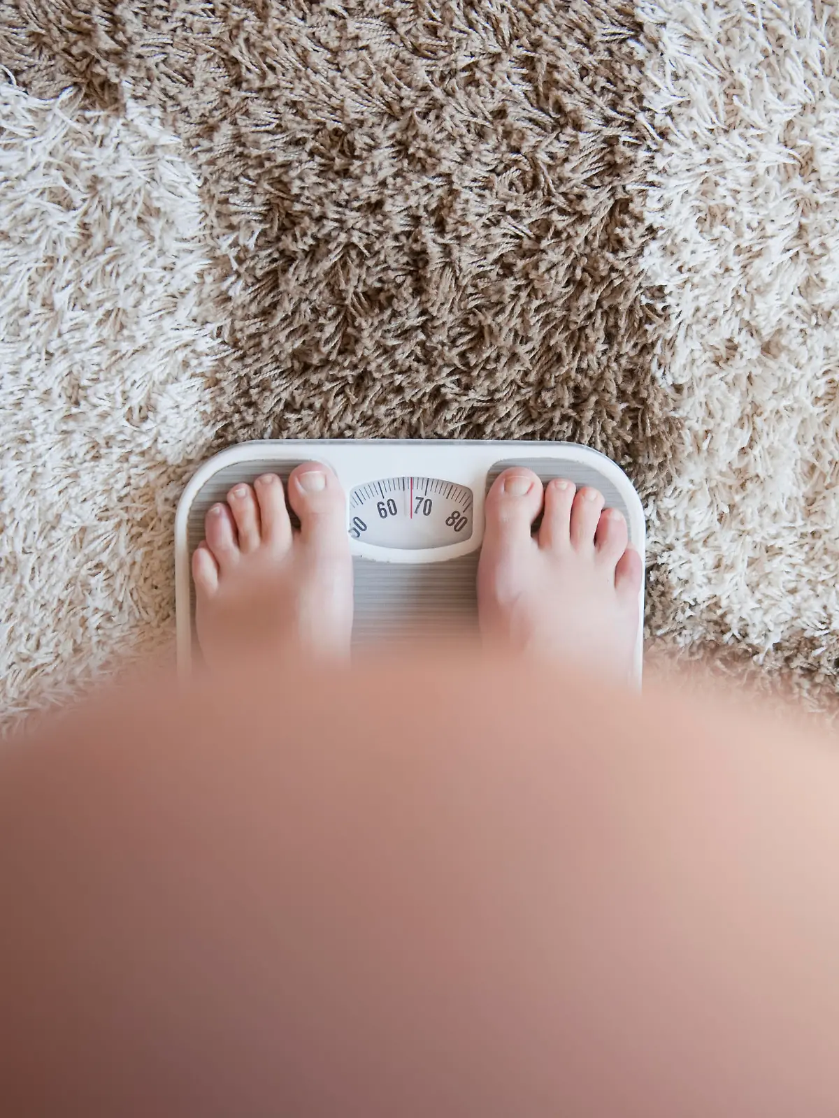 Pregnant woman weighting herself on a bathroom scale. View from above. No face. Focus on weight scale . Self portret Shallow dof