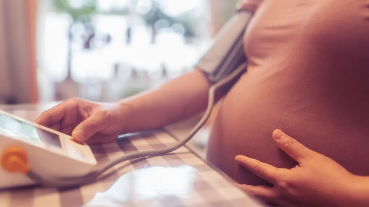 pregnant woman is taking her blood pressure