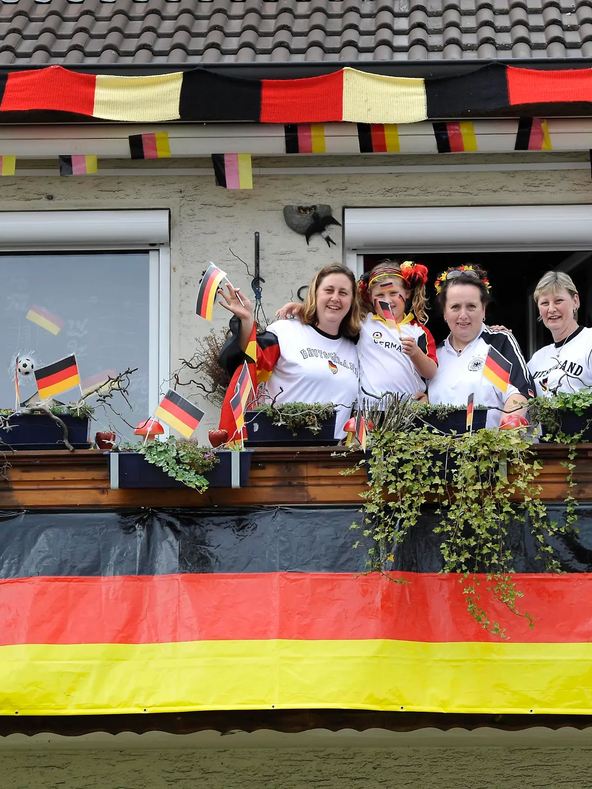 Fans der deutschen Nationalmannschaft in Nationaltrikots mit Deutschlandflaggen auf Balkon in geschmücktem Wohnhaus, Stuttgart, Baden-Württemberg, Deutschland, Europa || Modellfreigabe vorhanden