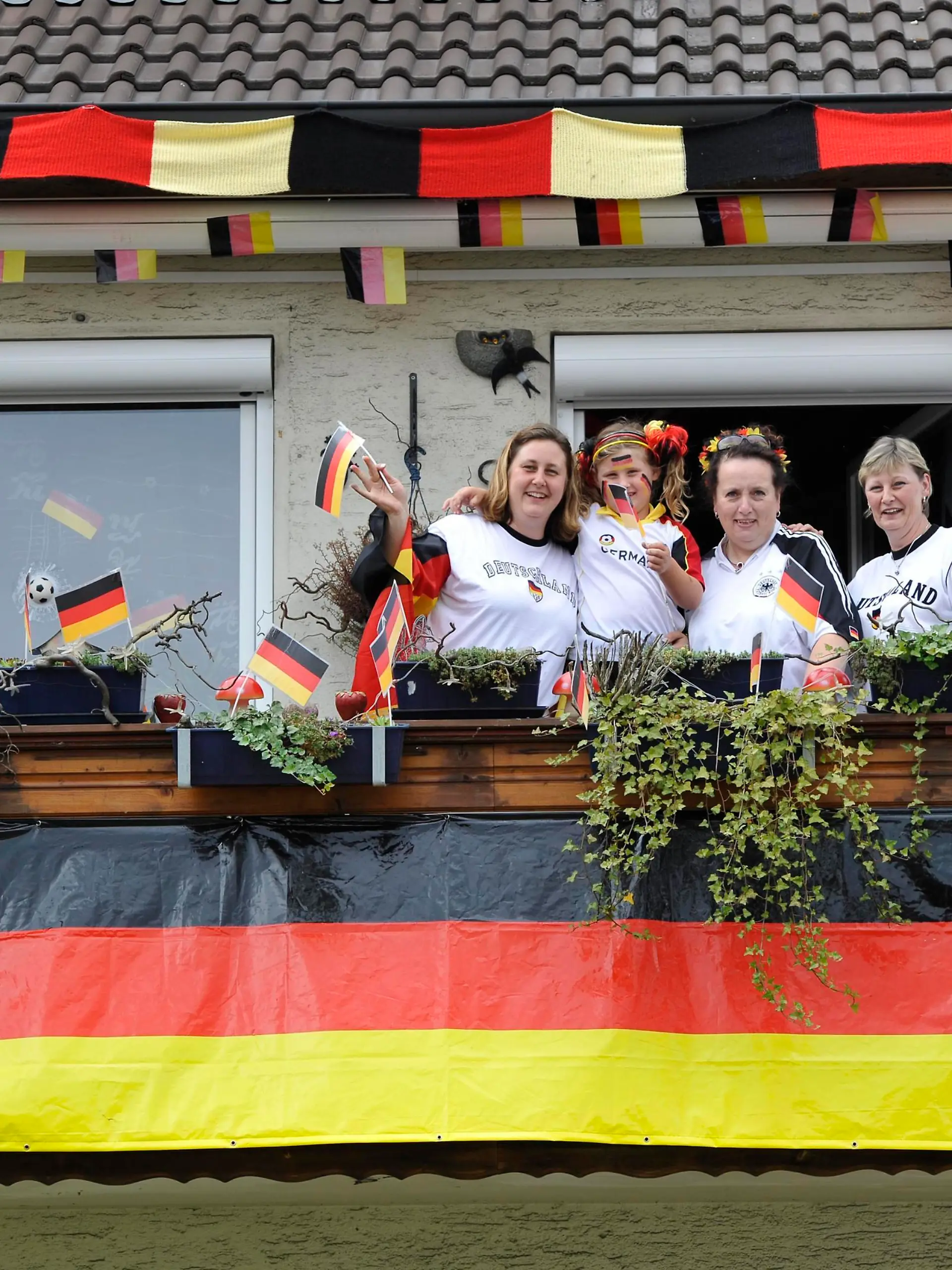 Fans der deutschen Nationalmannschaft in Nationaltrikots mit Deutschlandflaggen auf Balkon in geschmücktem Wohnhaus, Stuttgart, Baden-Württemberg, Deutschland, Europa || Modellfreigabe vorhanden