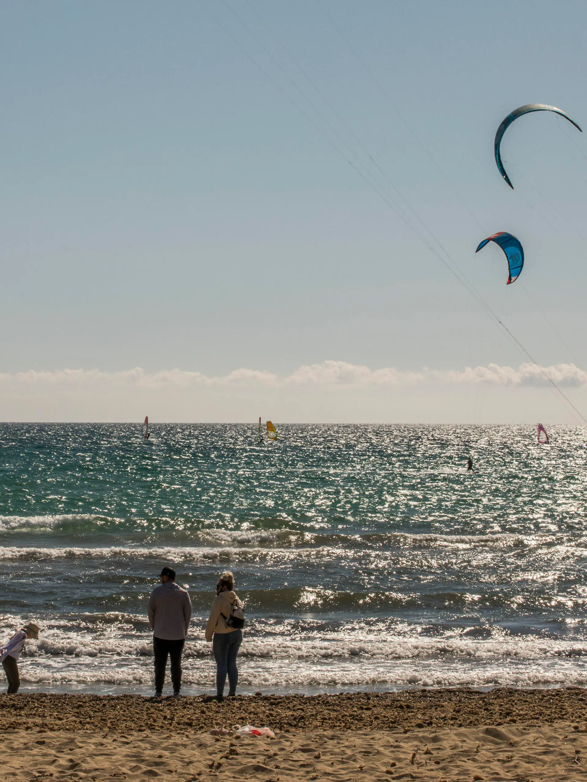 17.03.2021, Spanien, Mallorca: Eine Familie spaziert am Strand, während Kitesurfer den Tag das Meer vor Can Pastilla genießen. Schon vor dem Beginn der Osterferien ist auf der spanischen Mittelmeerinsel Mallorca die Zahl der Touristen gestiegen. Der größte Reiseanbieter Tui meldet kurz vor dem Start der vorgezogenen Ostersaison auf Mallorca anhaltend starke Buchungen. Foto: John-Patrick Morarescu/ZUMA Wire/dpa +++ dpa-Bildfunk +++