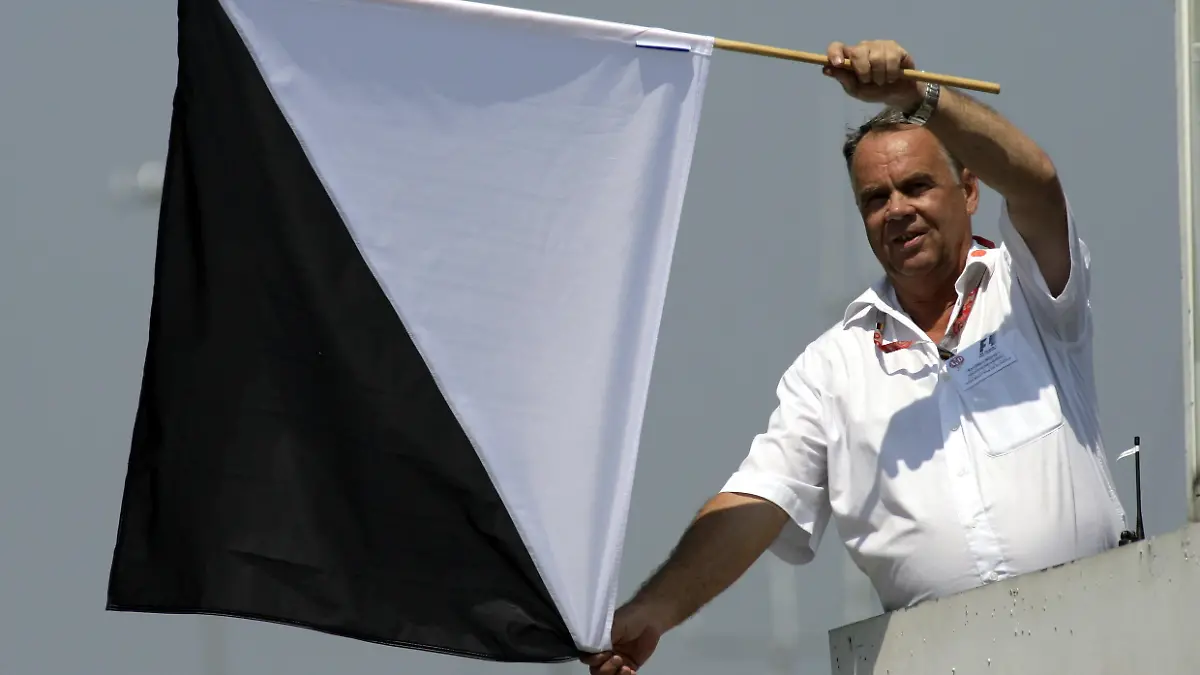 Ein Streckenposten zeigt die schwarz-weiße Flagge die unsportliches Verhalten anzeigt beim Großen Preis von Deutschland am 27.07.2006 auf dem Hockenheimring. Foto: Günter Schiffmann +++(c) Picture-Alliance / ASA+++