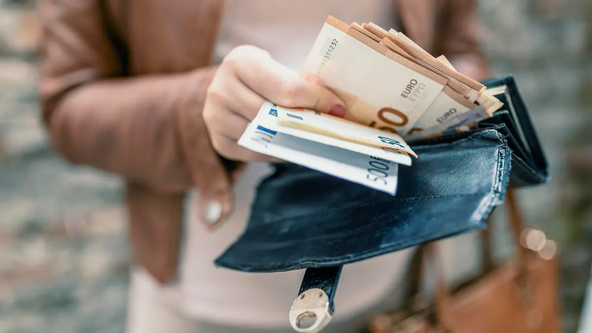Woman holding in hands wallet with euro money. City girl is taking out money from wallet