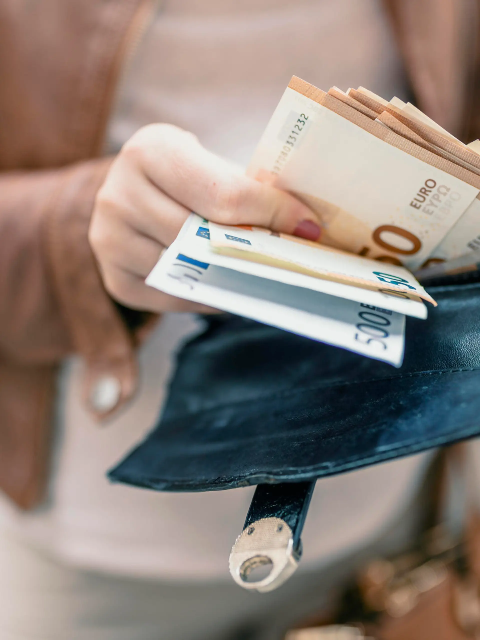Woman holding in hands wallet with euro money. City girl is taking out money from wallet