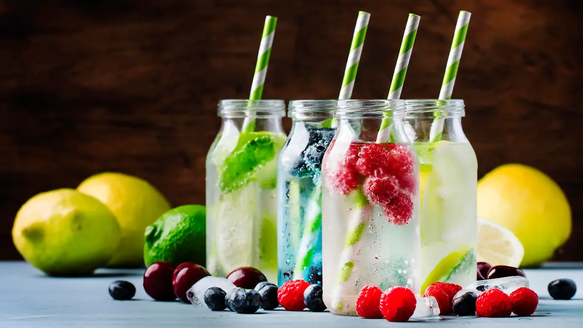 Summer drinks set. Berry, fruit and citrus non-alcoholic refreshing ice cold beverages and cocktails in glass bottles on blue background