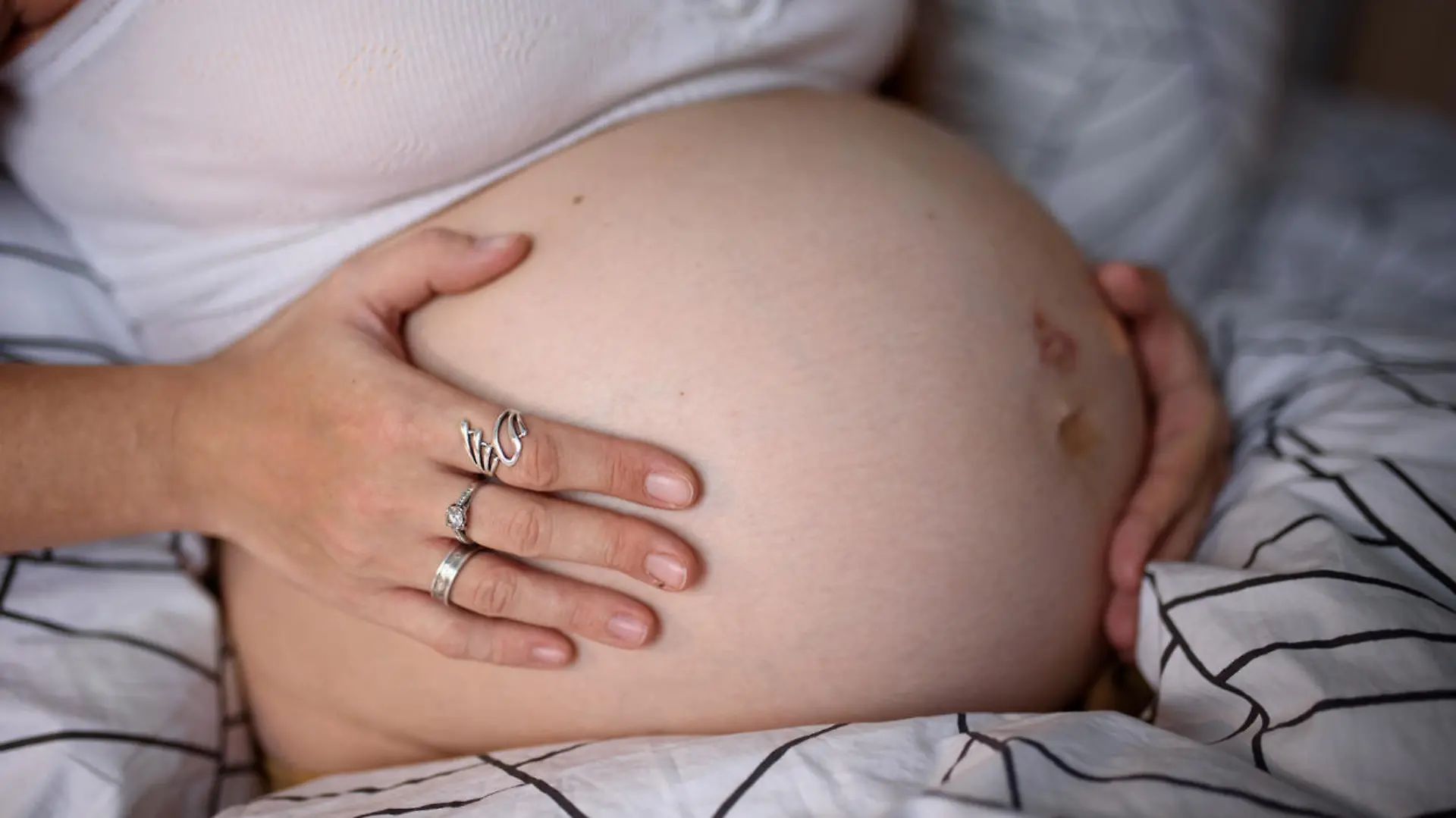A pregnant girl clings to her belly and worries before giving birth during a krantin. Self-isolation at home.