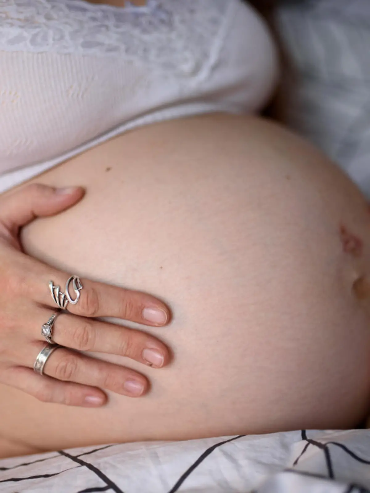 A pregnant girl clings to her belly and worries before giving birth during a krantin. Self-isolation at home.