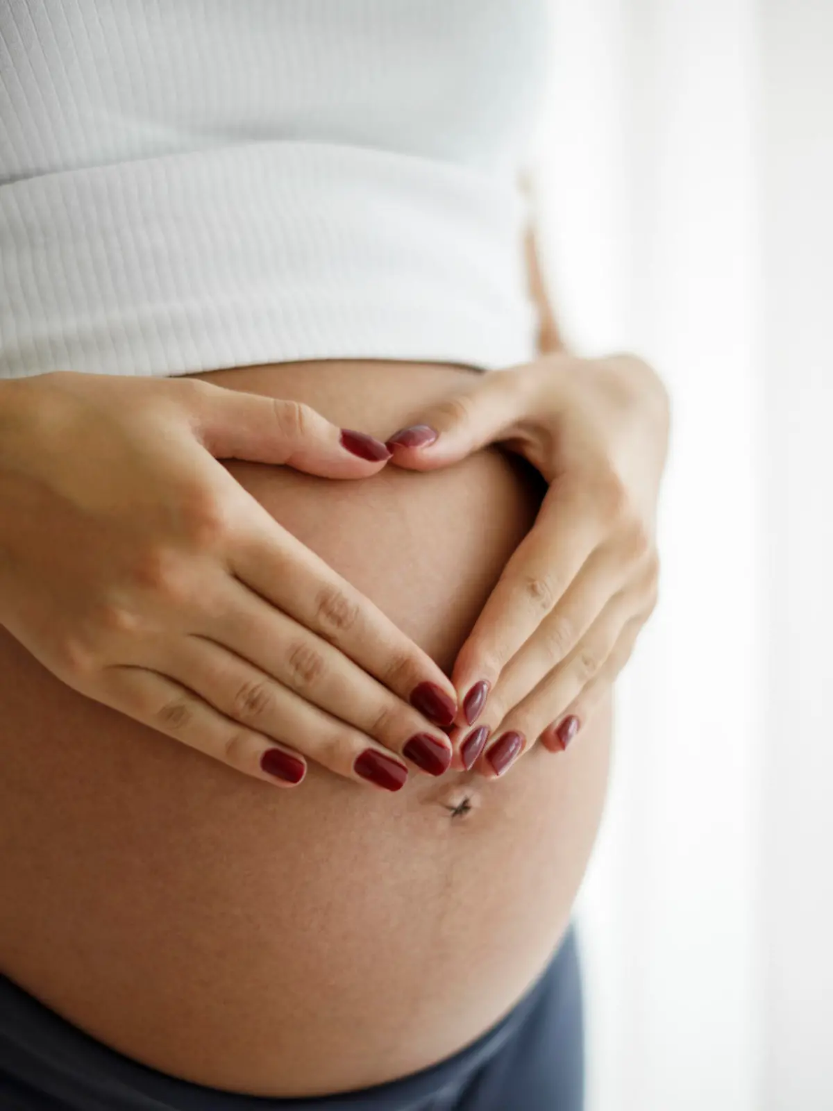 Pregnant woman holding her belly and making a heart shape