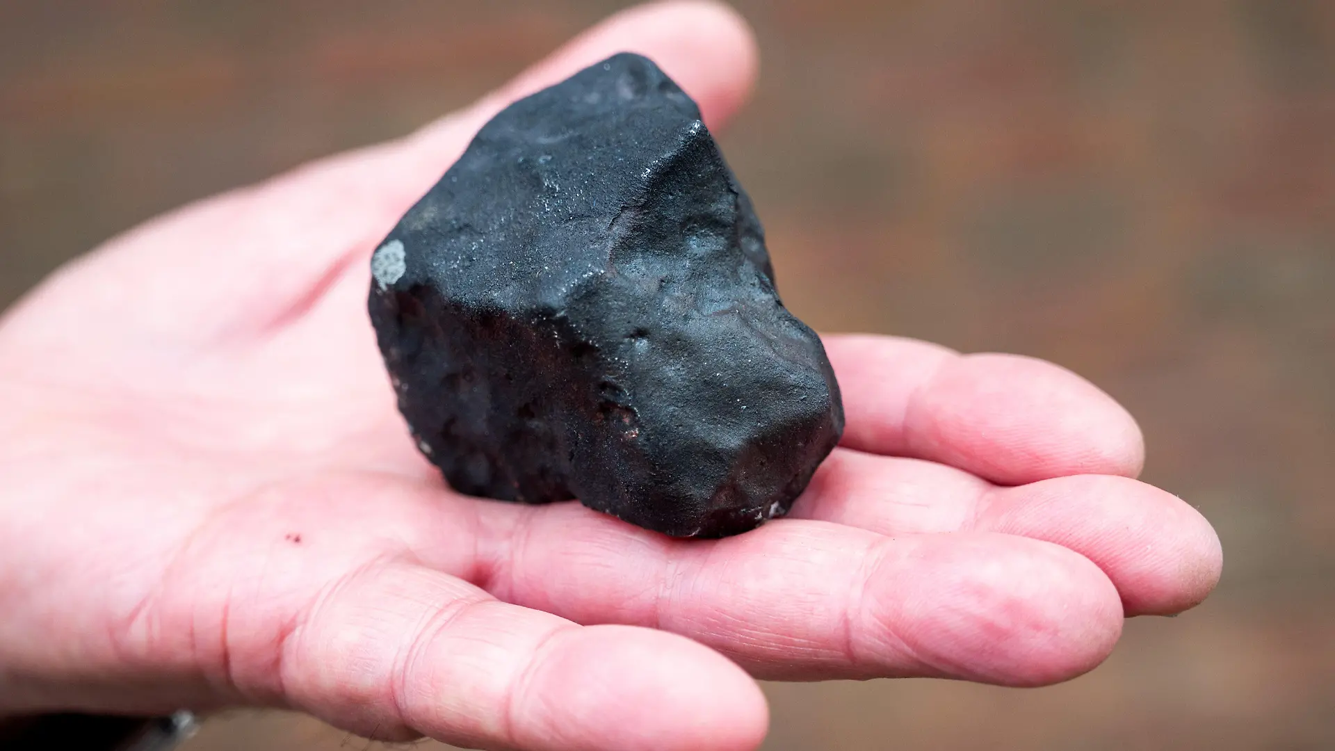 28.04.2023, Schleswig-Holstein, Elmshorn: Ein Hausbesitzer hält vor seinem Haus einen kleinen Meteoriten, der niedergegangen ist. Der Gesteinsbrocken von der Größe eines Tennisballs habe das Dach eines Hauses durchschlagen, dem Deutschen Zentrum für Luft- und Raumfahrt zufolge ist ein solches Ereignis sehr selten. (zu dpa ·Kleiner Meteorit trifft Haus in Schleswig-Holstein·) Foto: Daniel Bockwoldt/dpa/Daniel Bockwoldt +++ dpa-Bildfunk +++