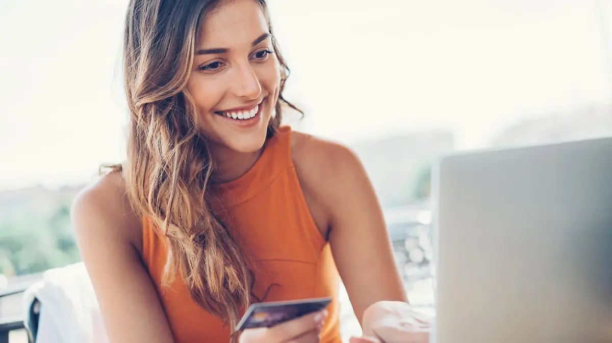 Beautiful young woman with credit card and laptop in cafe