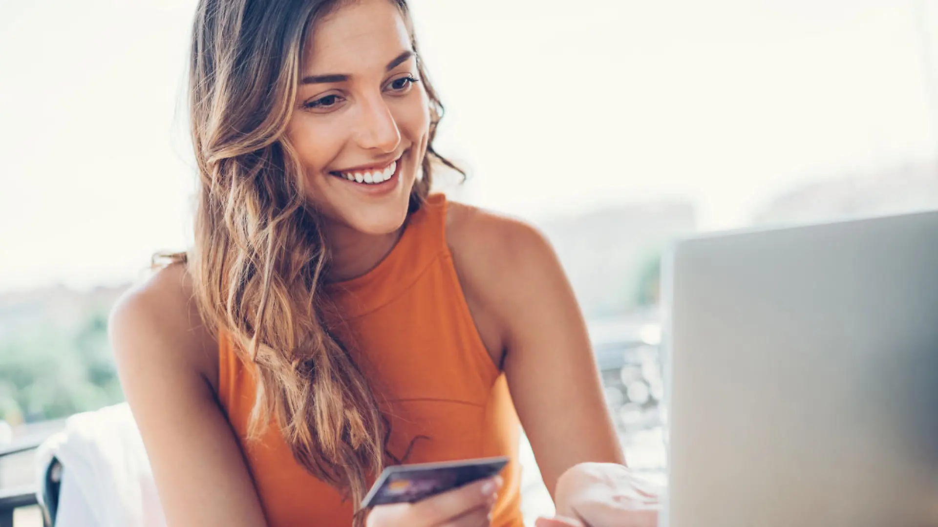 Beautiful young woman with credit card and laptop in cafe