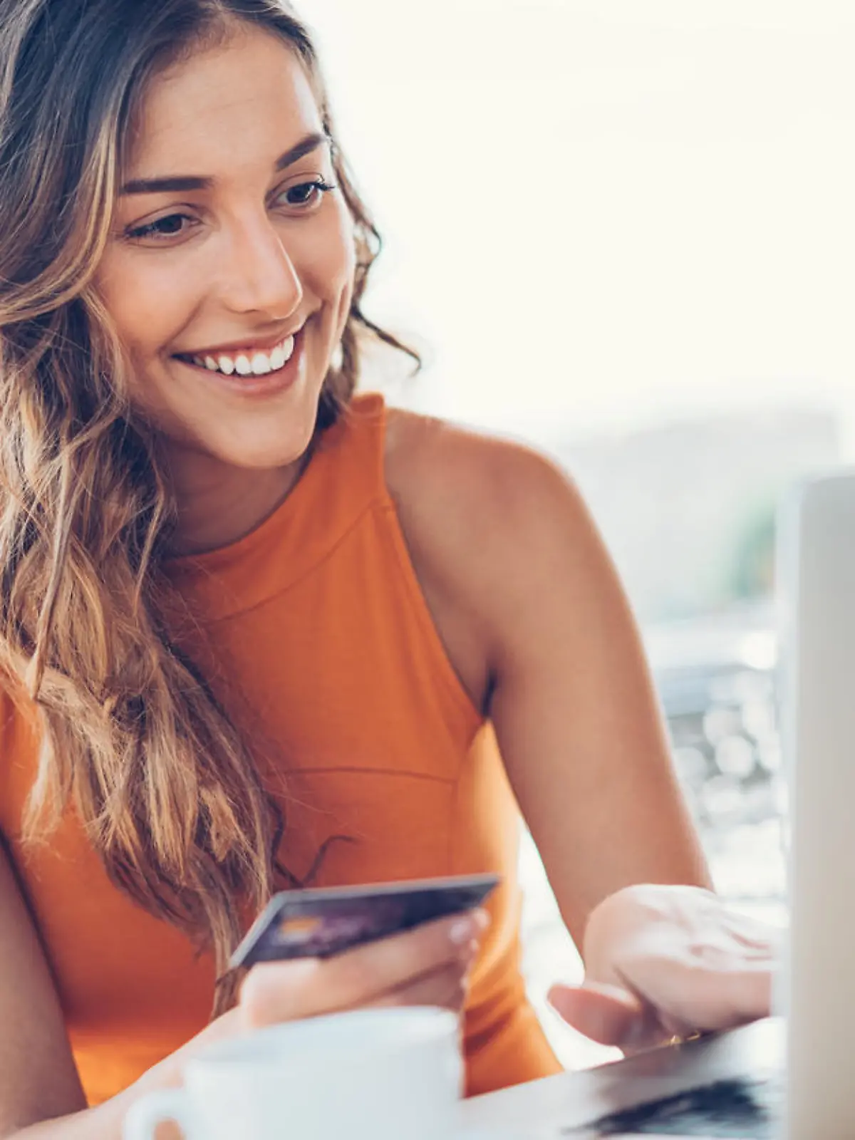 Beautiful young woman with credit card and laptop in cafe