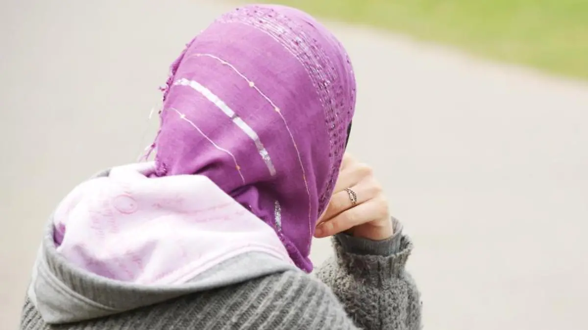 Eine junge Frau mit Kopftuch sitzt an einem Weg