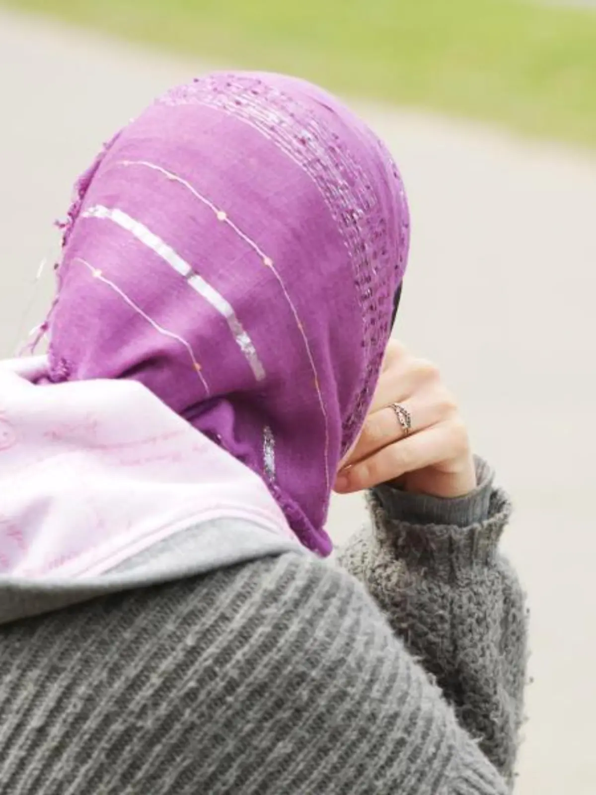 Eine junge Frau mit Kopftuch sitzt an einem Weg