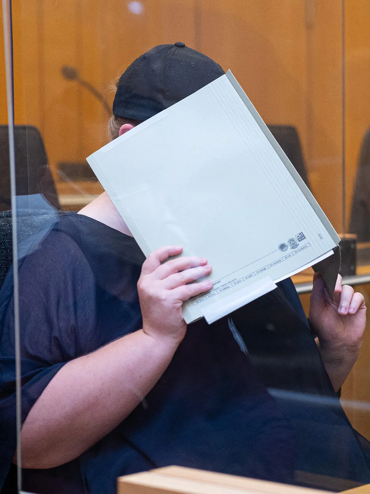 05.08.2021, Nordrhein-Westfalen, Münster: Zu Beginn des Prozesses im Missbrauchskomplex Münster sitzt die Mutter eines Opfers im Landgericht Münster und verdeckt ihr Gesicht mit einer Mappe. Die Anklage wirft der 31-Jährigen vor, den schweren sexuellen Missbrauch ihres heute elfjährigen Sohnes durch ihren Lebensgefährten nicht verhindert zu haben, obwohl sie davon wusste. Der IT-Techniker wurde im Hauptprozess zu 14 Jahren Haft und anschließender Sicherungsverwahrung verurteilt. Bis Ende September sind acht weitere Verhandlungstermine angesetzt. Foto: Guido Kirchner/dpa +++ dpa-Bildfunk +++