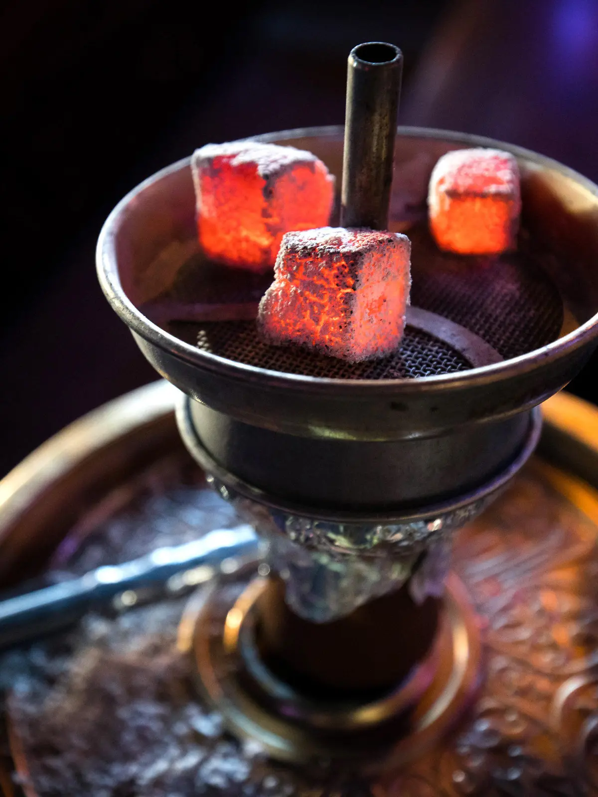 ARCHIV - 11.02.2019, Hamburg: Glühende Kohle liegt auf einem Metallsieb über dem Tabak im Kopf einer Wasserpfeife in einer Shisha-Bar. In NRW sind per Erlass neue strenge Regeln für Shisha-Bars in Kraft getreten. So müssen die Betreiber hochwirksame Lüftungsanlagen einbauen, Warnschilder am Eingang aufhängen und Warngeräte für Kohlenmonoxid (CO) in sämtlichen Gasträumen sowie im Thekenbereich, den Fluren und den Toiletten anbringen. Foto: Christian Charisius/dpa +++ dpa-Bildfunk +++