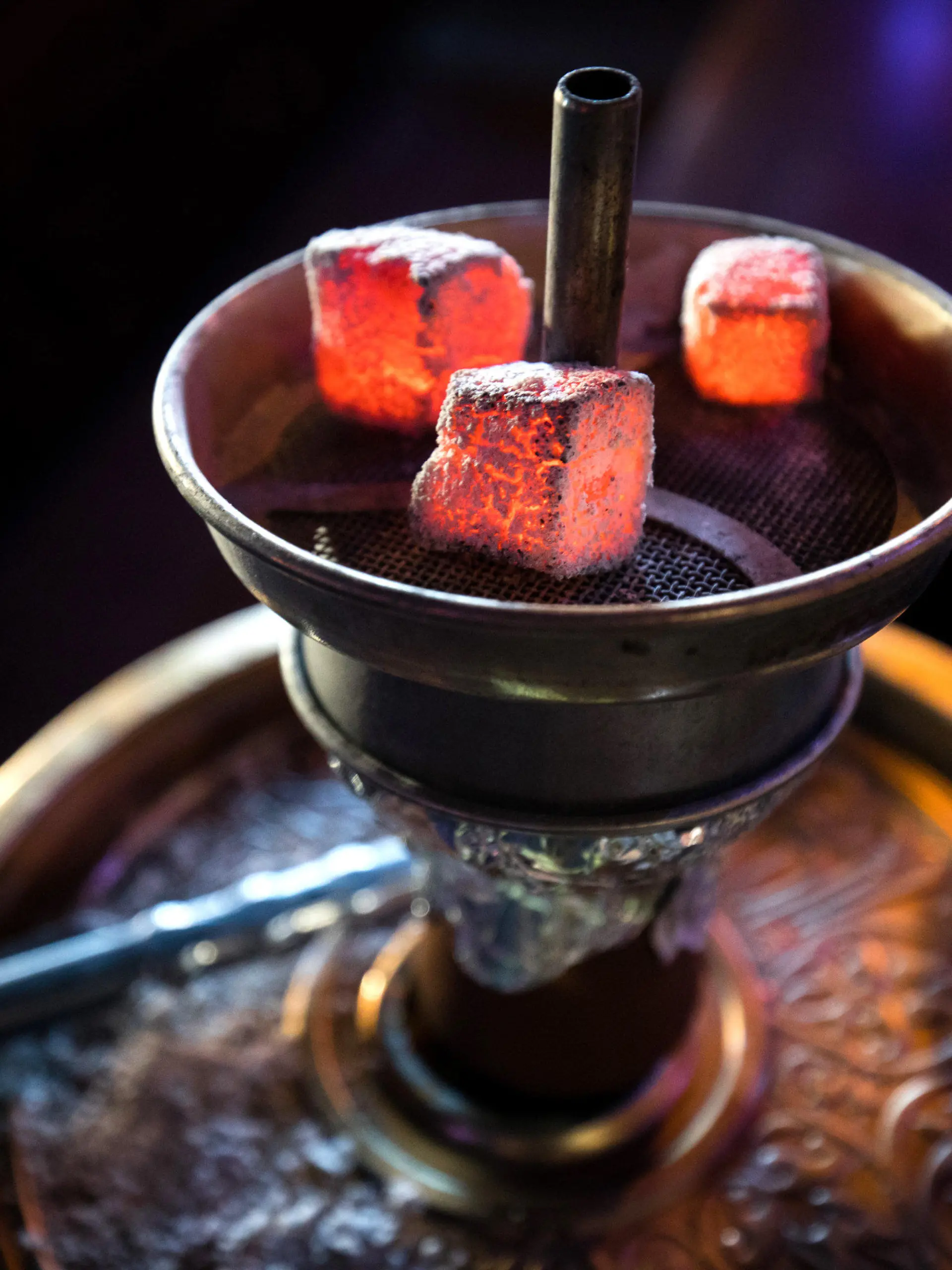 ARCHIV - 11.02.2019, Hamburg: Glühende Kohle liegt auf einem Metallsieb über dem Tabak im Kopf einer Wasserpfeife in einer Shisha-Bar. In NRW sind per Erlass neue strenge Regeln für Shisha-Bars in Kraft getreten. So müssen die Betreiber hochwirksame Lüftungsanlagen einbauen, Warnschilder am Eingang aufhängen und Warngeräte für Kohlenmonoxid (CO) in sämtlichen Gasträumen sowie im Thekenbereich, den Fluren und den Toiletten anbringen. Foto: Christian Charisius/dpa +++ dpa-Bildfunk +++