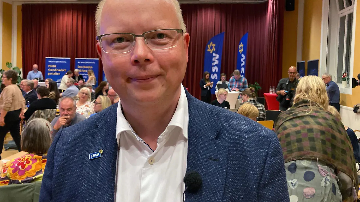 26.09.2021, Schleswig-Holstein, Flensburg: Stefan Seidler, Spitzenkandidat des Südschleswigschen Wählerverbandes (SSW), lächelt auf der Wahlparty der Partei der dänischen Minderheit und der nationalen Friesen in die Kamera. Die Partei ist von der Fünf-Prozent-Hürde befreit. Foto: Birgitta von Gyldenfeldt/dpa +++ dpa-Bildfunk +++
