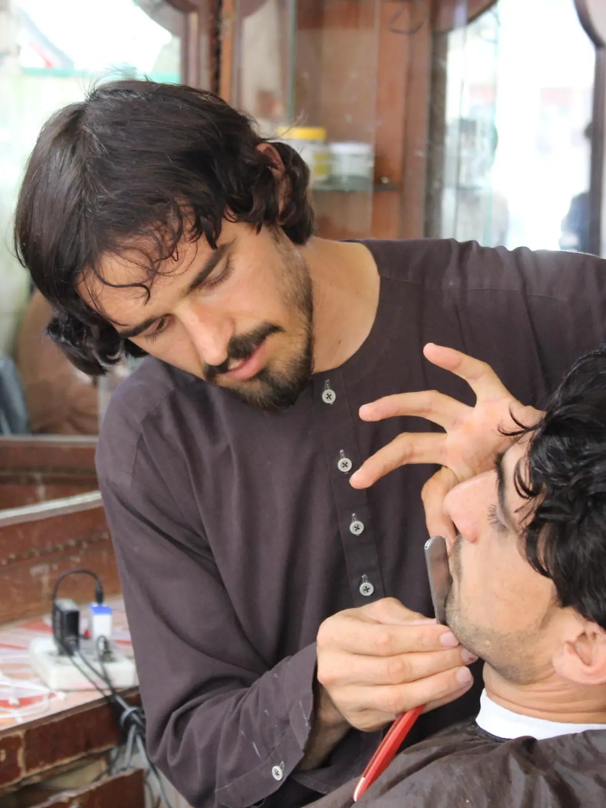 KHOST, AFGHANISTAN - SEPTEMBER 23: A barber cuts shaves beard at a shop in Khost, Afghanistan on September 23, 2021. Barbers in Afghanistan's Khost province say, with the advent of the Taliban, their business has deteriorated and their customers have dwindled. Sardar Shafaq / Anadolu Agency