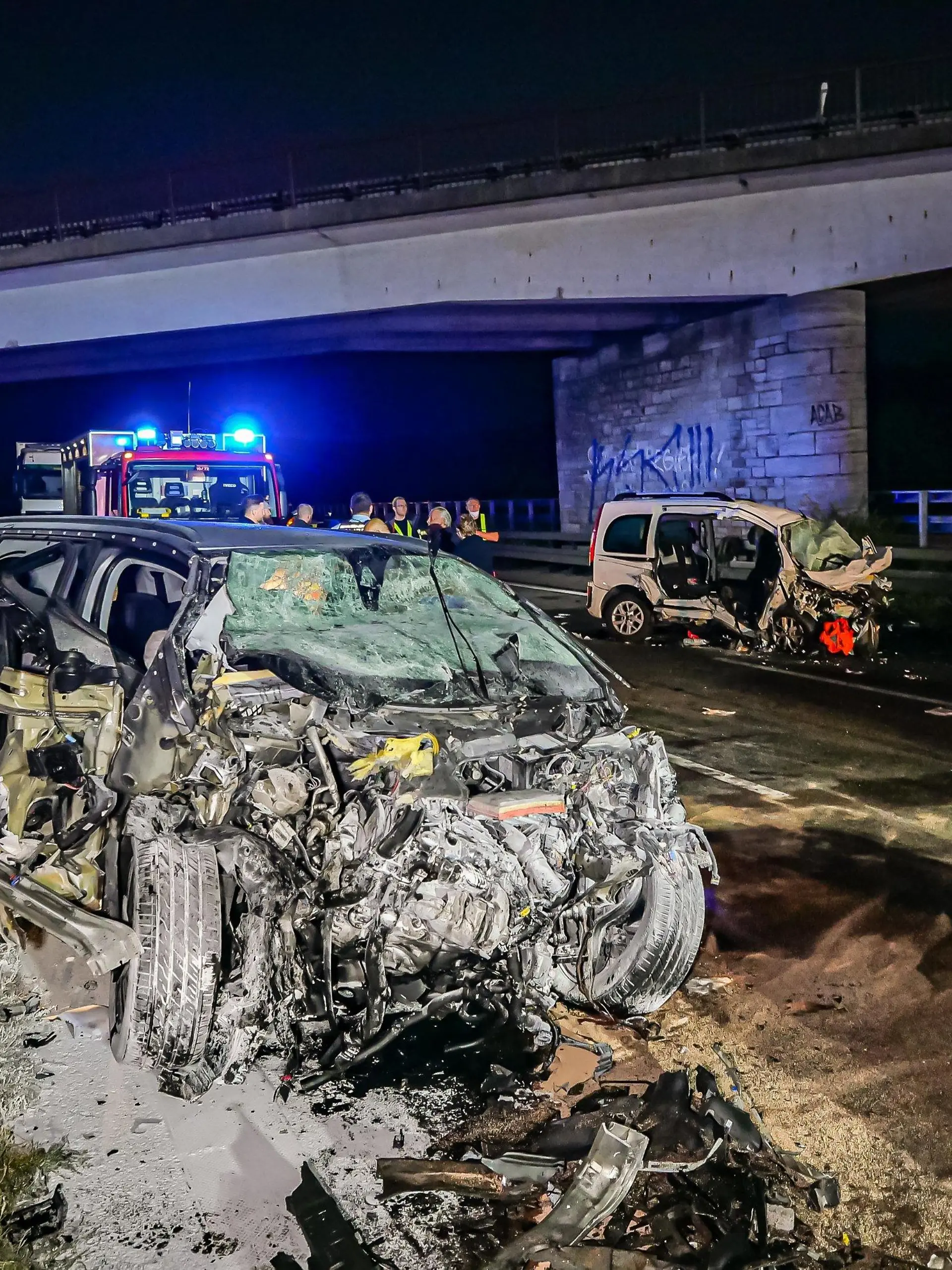 26.09.2021, Baden-Württemberg, Pforzheim: Feuerwehrleute stehen am Unfallort. Drei Menschen sind am frühen Sonntagmorgen bei einem Unfall auf der Autobahn 8 bei Pforzheim ums Leben gekommen, darunter der 35 Jahre alte Unfallverursacher. Der Mann war nach Angaben der Polizei mit seinem Wagen von einem Parkplatz aus entgegen der Fahrtrichtung auf die Autobahn aufgefahren. Dort prallte das Auto (l) frontal in einen anderen Wagen (hinten r): Zwei der Insassen dieses Wagens starben, zwei weitere wurden schwer verletzt. Foto: Alexander Hald/VMD-Images/dpa +++ dpa-Bildfunk +++