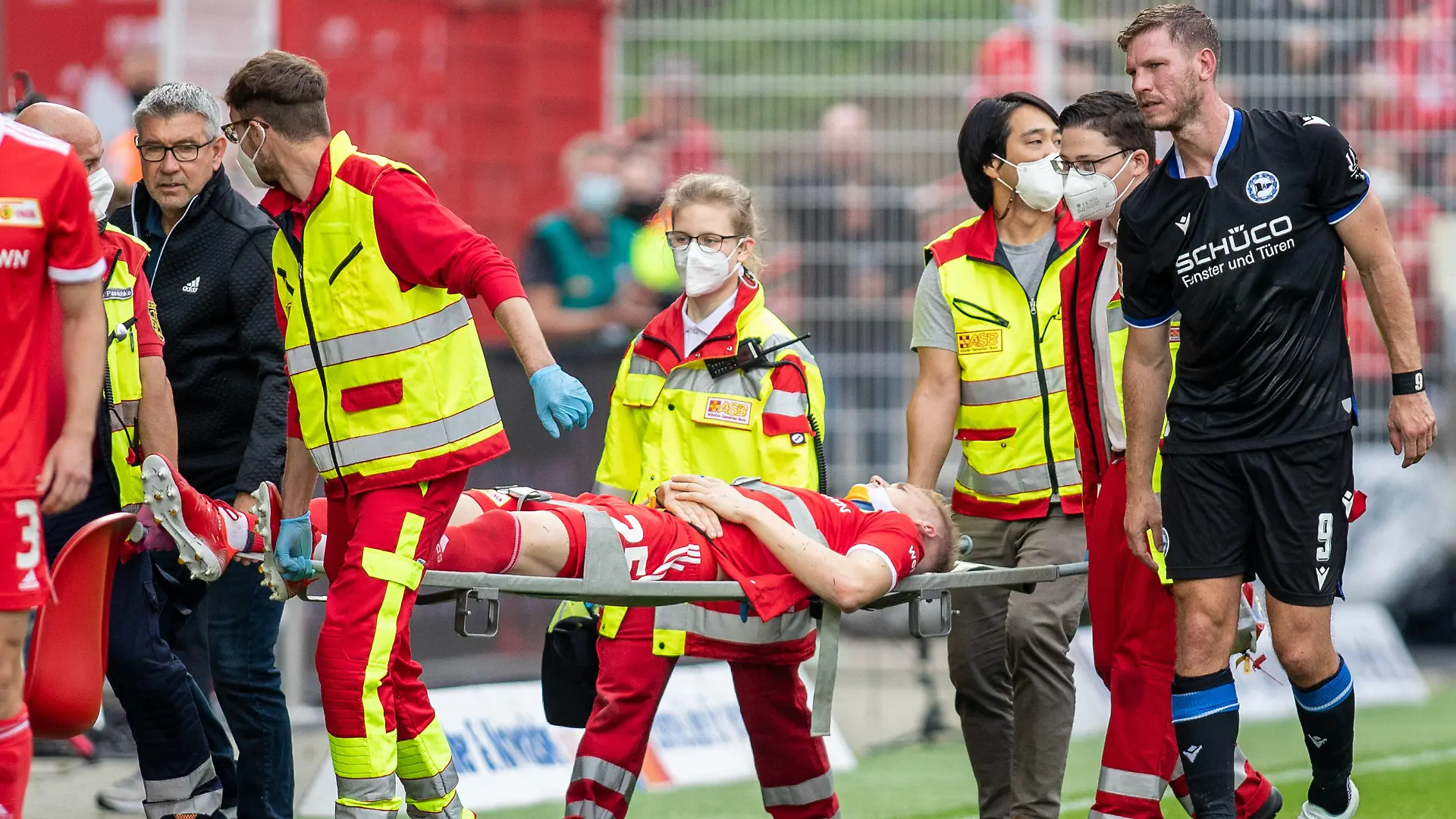 25.09.2021, Berlin: Fußball, Bundesliga, 6. Spieltag, 1. FC Union Berlin - Arminia Bielefeld, Stadion An der Alten Försterei: Berlins Timo Baumgartl wird nach einem Zusammenstoß mit Fabian Klos (r) von Arminia Bielefeld vom Spielfeld getragen. Links geht Berlins Trainer Urs Fischer. Foto: Andreas Gora/dpa - WICHTIGER HINWEIS: Gemäß den Vorgaben der DFL Deutsche Fußball Liga bzw. des DFB Deutscher Fußball-Bund ist es untersagt, in dem Stadion und/oder vom Spiel angefertigte Fotoaufnahmen in Form von Sequenzbildern und/oder videoähnlichen Fotostrecken zu verwerten bzw. verwerten zu lassen. +++ dpa-Bildfunk +++
