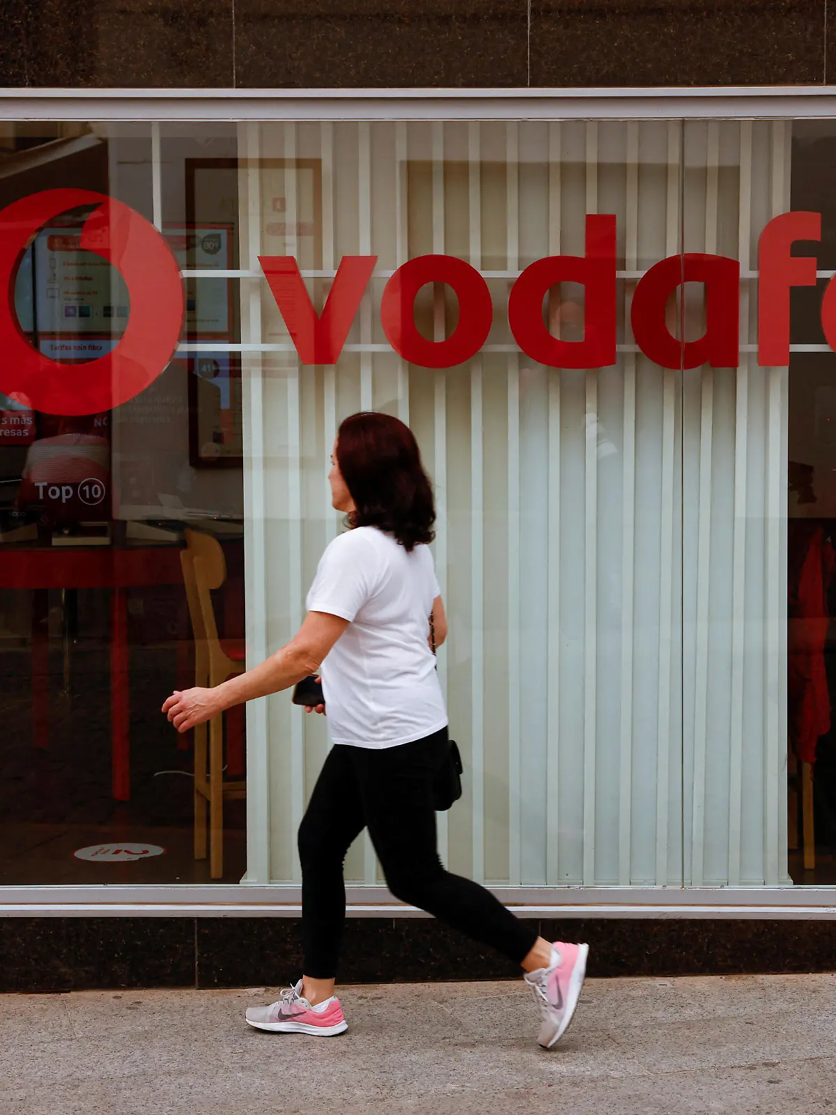 FILE PHOTO: A woman walks past a Vodafone store in Ronda, Spain, October 3, 2022. REUTERS/Jon Nazca/File Photo