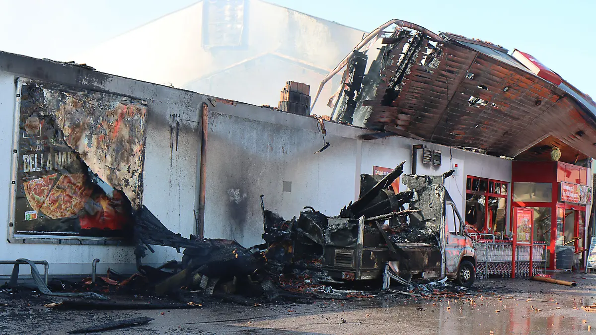 24.09.2021, Bayern, Allershausen: Nach einem Großbrand in einem Supermarkt sind Teile des Daches eingestürzt, ein verbrannter Kleinlaster steht an dem Supermarkt.  Das Feuer war am 24.09.2021 morgens in einem Penny-Markt ausgebrochen. Das Freisinger Landratsamt hatte die Bevölkerung aufgerufen, wegen der starken Rauchentwicklung Fenster und Türen geschlossen zu halten. Am späten Vormittag wurde die Warnung aufgehoben. Hinweise darauf, dass Menschen verletzt wurden, gab es demnach zunächst nicht. Foto: Mario Obeser/dpa +++ dpa-Bildfunk +++