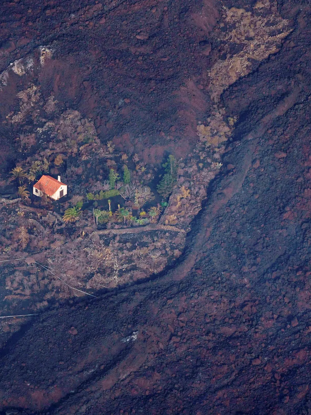 Lava flows surrounded a house following the eruption of a volcano in the Cumbre Vieja national park at El Paso, on the Canary Island of La Palma, Spain September 23, 2021. Ramon de la Rocha/Pool via REUTERS